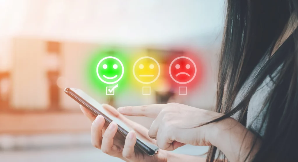 Ein grüner Smiley ist angekreuzt, neben einem gelben und einem roten Smiley. Eine Person hält ein Handy und versucht die Core Web Vitals zu optimieren.